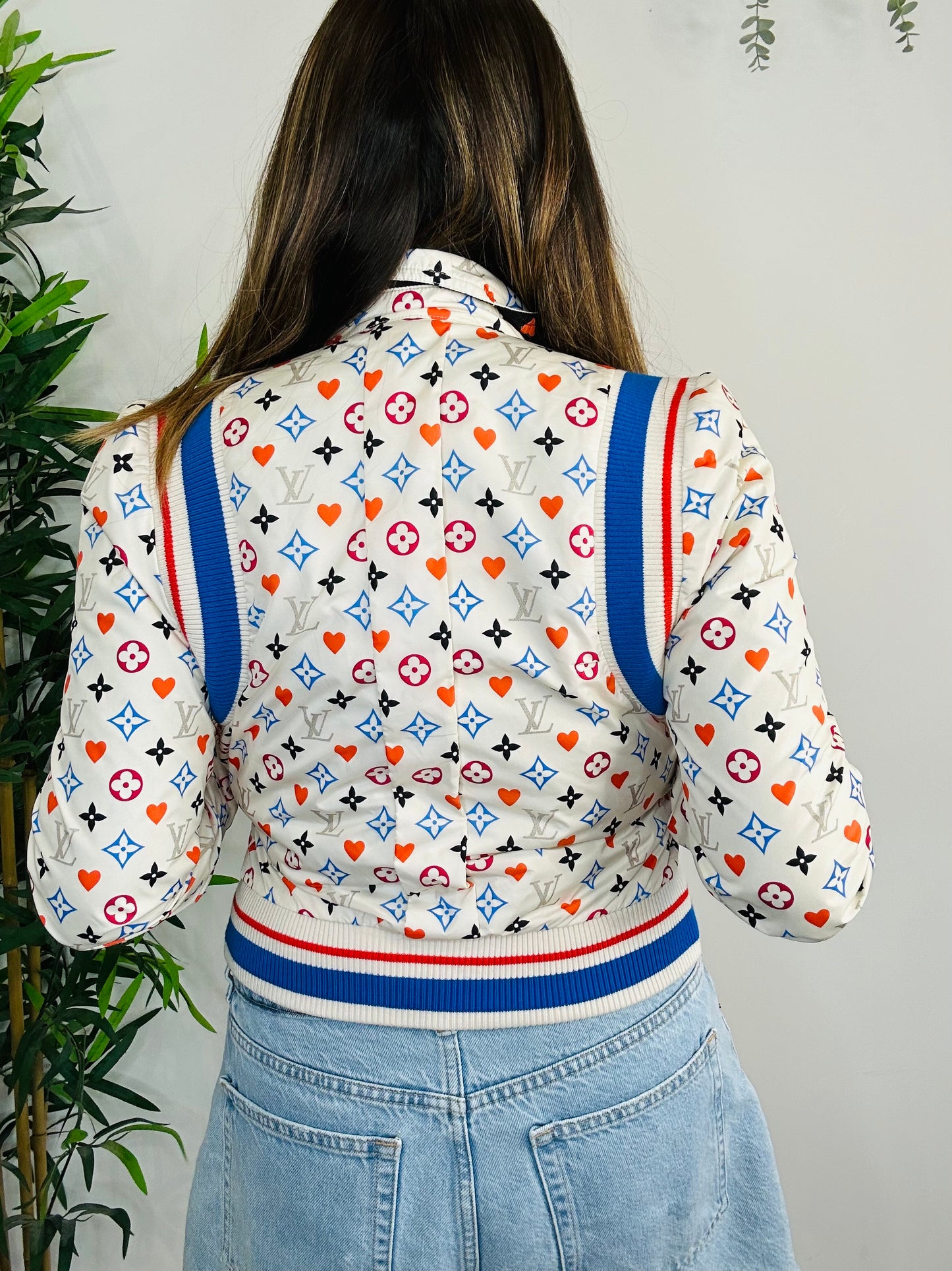 Person wearing a patterned LV jacket with blue trim against a neutral background
